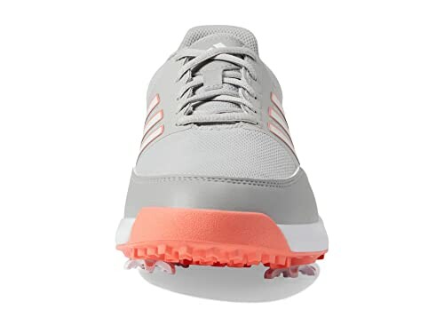 Front view of a gray golf shoe with orange spikes.