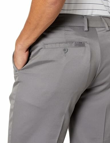 Back view of person wearing gray trousers with hand in pocket.