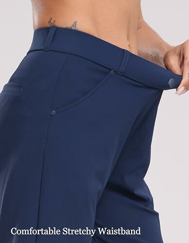 Person showing stretchy waistband on navy pants.